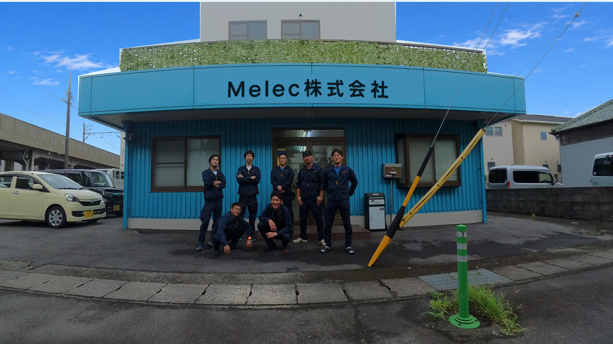 Melec株式会社の事務所前に集まるスタッフ